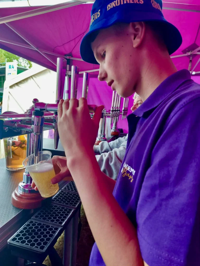 Staff pouring a pint from a tap.